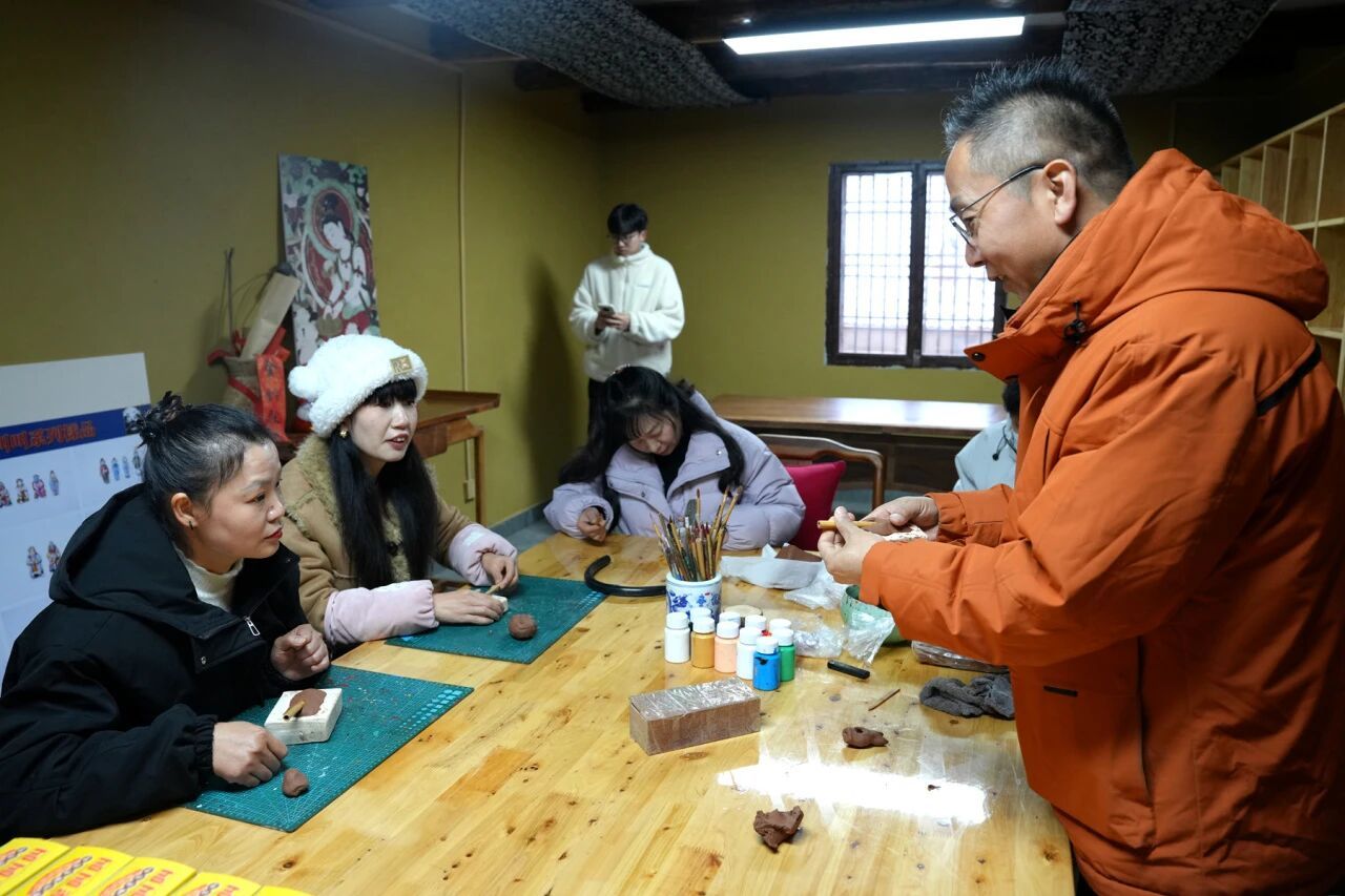 在泥叫叫工作坊，游客跟着鱼化“泥叫叫”第五代传承人杨帆（右一）制作“泥叫叫”。（本文图片由高文亚拍摄）
